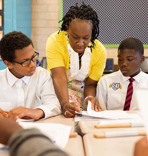 Teacher teaching two students at their desk